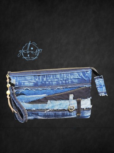 Denim clutch bag with a textured design and a zipper closure against a dark background.