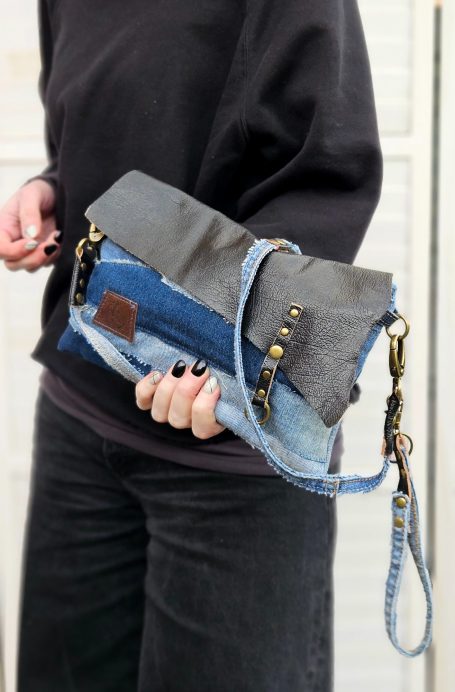 Small patchwork denim clutch bag with chain strap held in hand