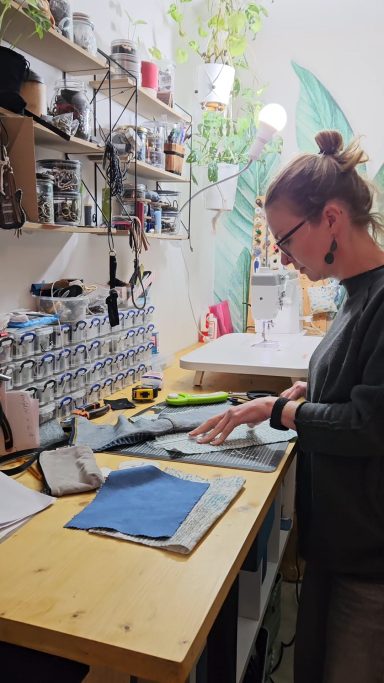 Gabus81 maker working at a sewing table with denim pieces for handmade upcycled bags
