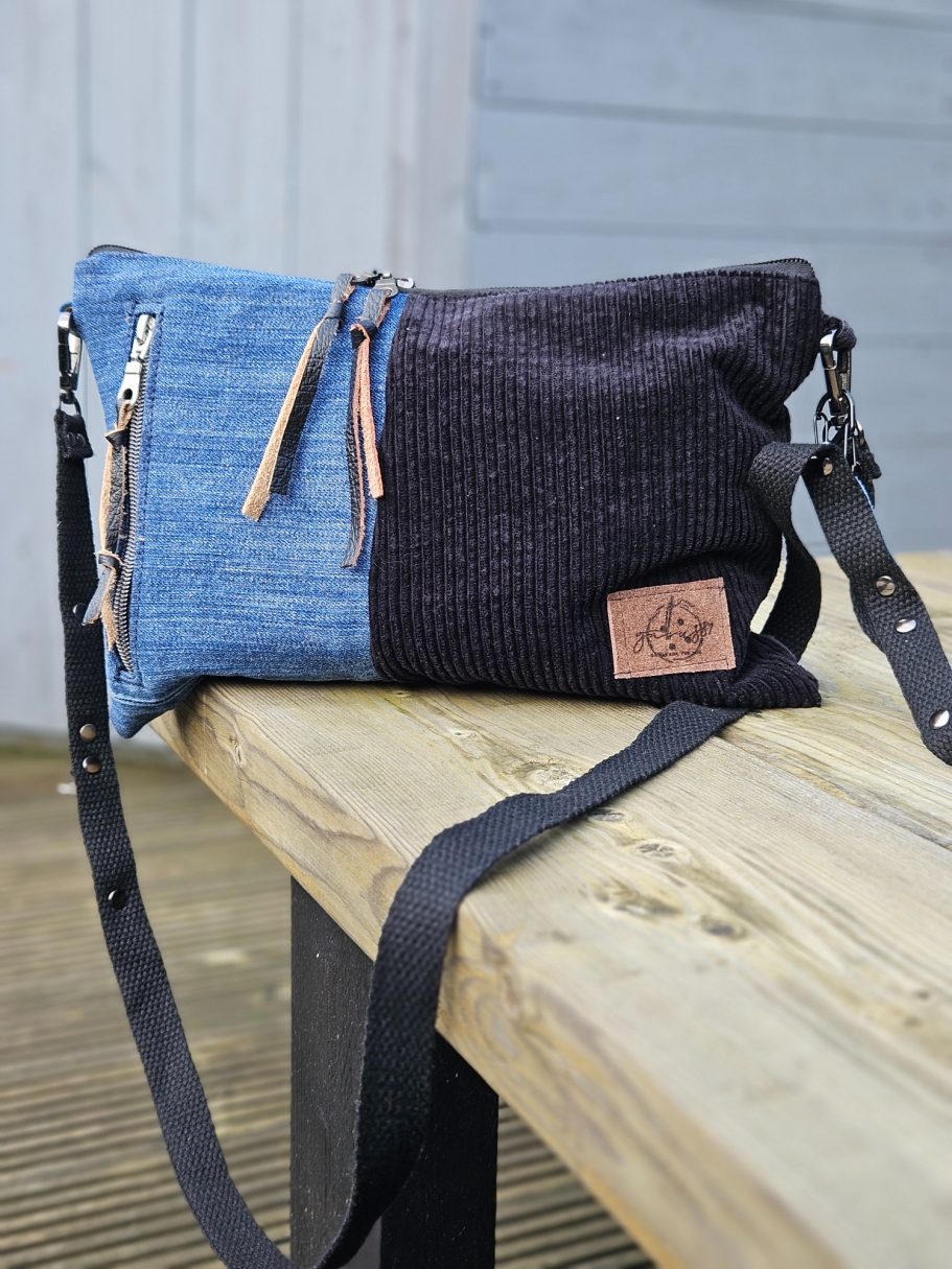 Two-tone fabric crossbody bag in denim and dark corduroy with leather accents.