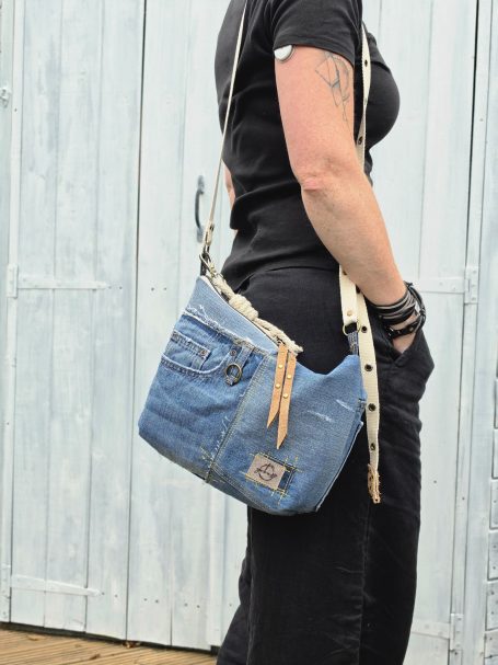 Denim crossbody bag with adjustable strap worn at the hip