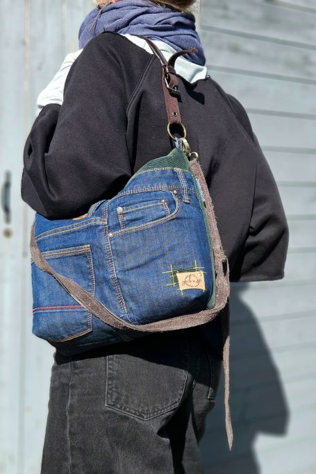 Blue denim crossbody bag worn on shoulder with patchwork denim design and practical everyday size