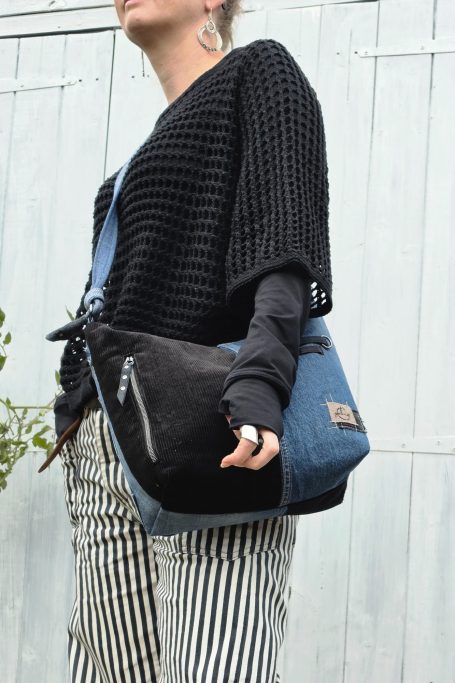 Black and blue denim crossbody bag worn at the hip with a shoulder strap.
