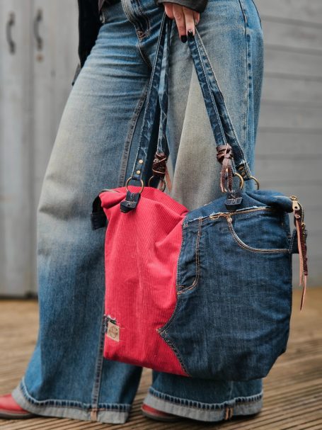 Large denim tote bag with red side panel carried on the shoulder