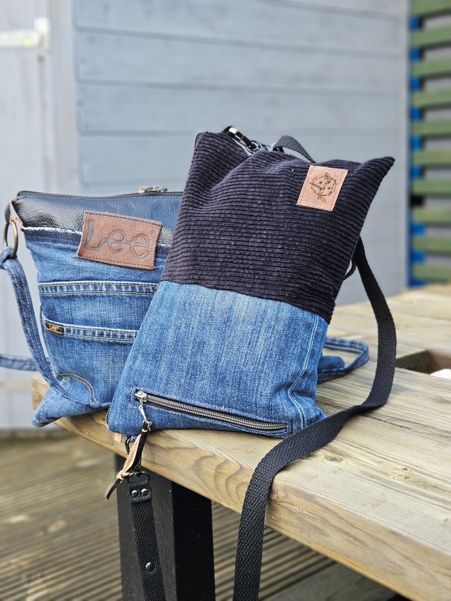 Two stylish bags made from denim, one larger with a shoulder strap and a smaller one beside it.
