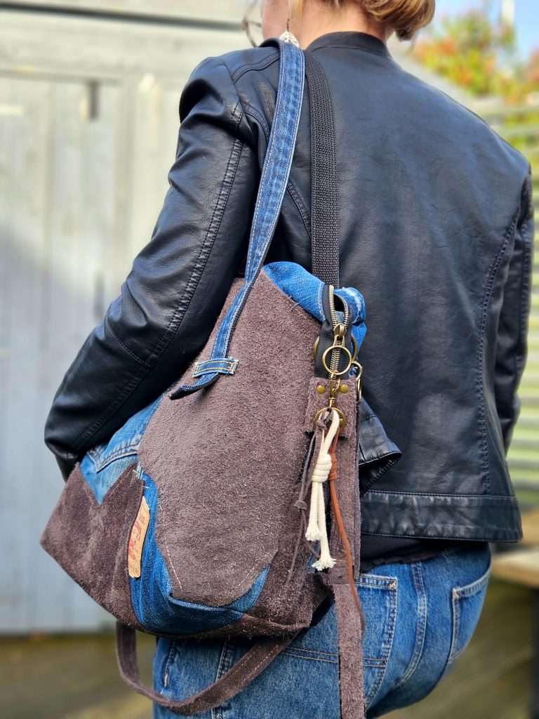 A person carrying a stylish brown and blue shoulder bag with a keychain attached.