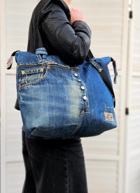Large blue denim tote bag worn on the shoulder.