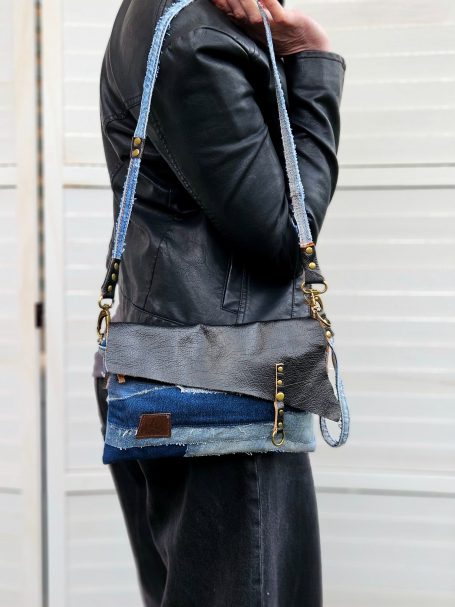Denim crossbody clutch bag worn on shoulder with long strap and slim rectangular shape