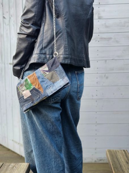 Denim clutch bag worn on shoulder with long strap and soft rectangular shape
