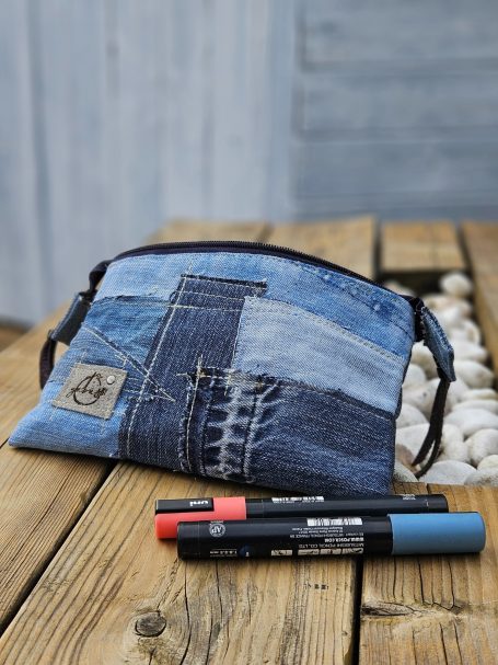 Blue patchwork denim zip pouch displayed with pens on a wooden table.
