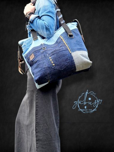 A person wearing a denim jacket, holding a stylish patchwork tote bag.