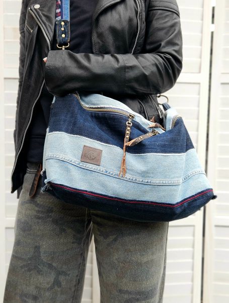 Oversized denim crossbody bag worn across body with light and dark denim patchwork design