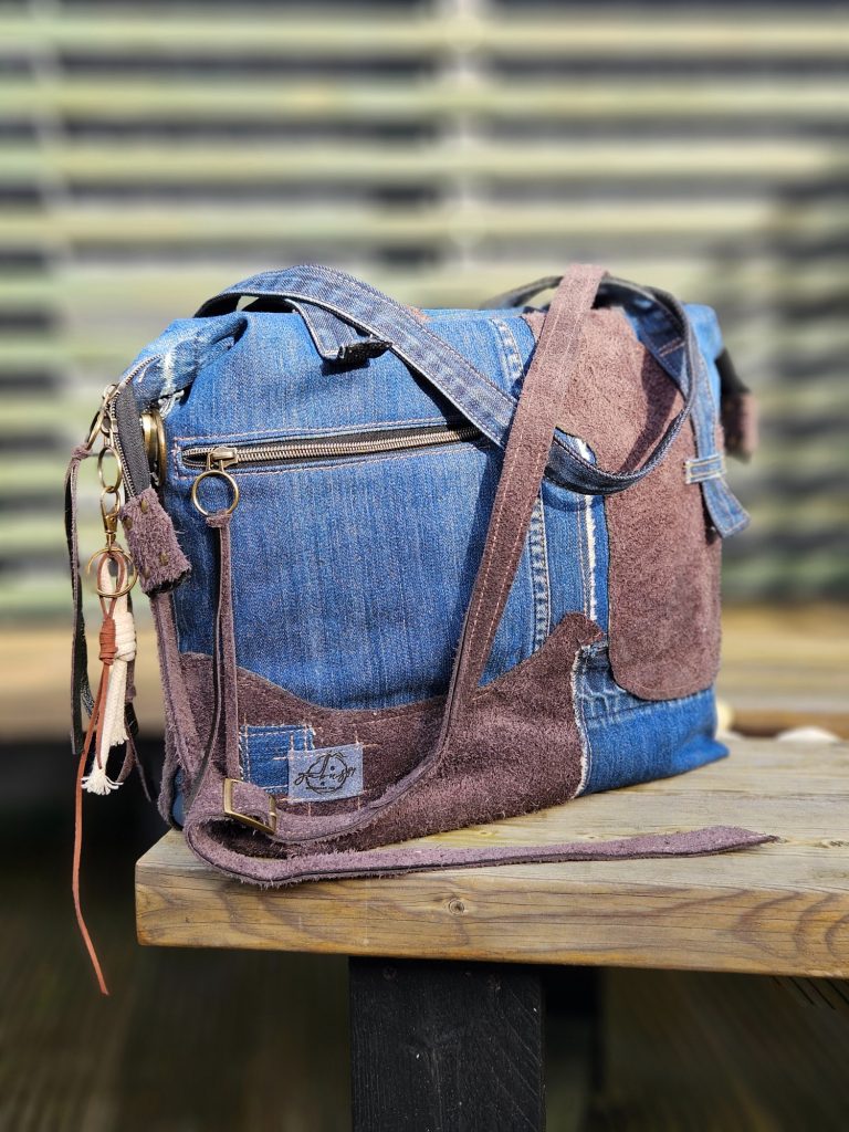 A stylish handbag made from denim and brown suede on a wooden surface.